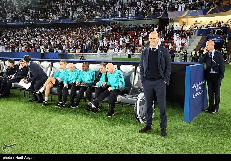 Zinedine Zidane in piedi davanti alla panchina del Real Madrid